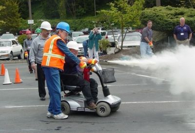 CERT volunteer in wheelchair extinguishing a fire.